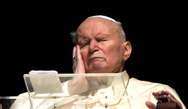 Pope John Paul II touches his face as he appears from the window of his private apartment at the Vatican on March 30, 2005.