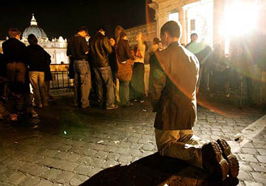 A faithful kneels in prayer in front of Saint Peter's Basilica at the Vatican on March 31.