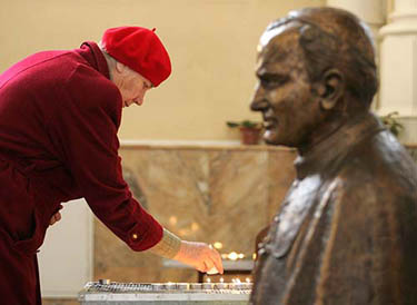 A woman places a lit candle next to a bust of Pope John Paul II inside the Church of the Immaculate Conception in Moscow on April 1. 