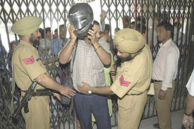 Police personnel frisk a man following a hoax bomb call on the premises of Punjab National Bank in Jalandhar on Saturday.