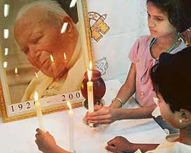 Children pay obeisance to the portrait of Pope John Paul II in a city church