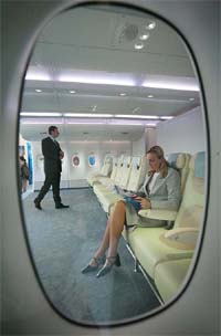 An Airbus employee poses in an economy-class seat of an Airbus A 380 mock-up cabin section at the Aircraft interiors Expo 2005 in Hamburg