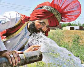 Bhangra dancer quenches thirst while taking a break in the countryside of Ludhiana on Wednesday