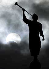 A statue is seen against a partial solar eclipse in Bogota
