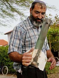 An Israeli settler holds a part of a rocket after an attack at the Neve Dekalim settlement in Gush Katif, Gaza Strip