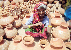 An elderly potter woman takes orders on a mobile phone for her hand-made earthen pots in Patna on Monday.