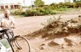 A cyclist walks through Patiala Ki Rao choe as the bridge connecting Nayagaon with Nada village has been inundated. 