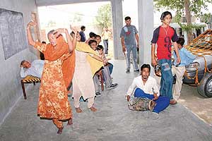 Girls perform on the beat of the dhol as men from a marriage party look on while resting on the charpoys in Government Middle School of Bhullar village in Noormahal subdivision of Jalandhar district on Wednesday. 
