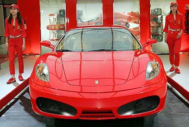 Models stand next to a Ferrari F430, which is displayed at a press day event of Ferrari exhibition section during Auto Shanghai, 2005, exhibition on Thursday in China. Top world automakers are showcasing new models in Shanghai in hope of reviving languishing domestic sales.
