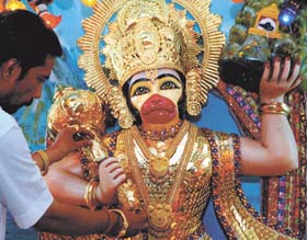 A purohit decorating the idol of Hunuman with 5555 silver coins on the eve of Hanuman Jayanti at Gauri Shanker temple in the Capital
