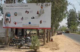 A hoarding of a private school atop trees on the Jalandhar-Hoshiarpur road