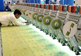 An exhibitor arranges a yarn reel at a knitting machine on display at an exhibition in Karachi on Monday. Inaugurating the three-day long exhibition, Pakistani Textile Minister Mushtaq Ali Cheema announced that the government was to create a textile and garment city in Karachi. 