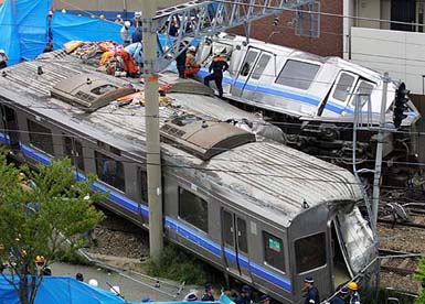 Rescuers work atop a derailed commuter train that smashed into an apartment building in Amagasaki, western Japan, on Monday.