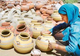 A woman potter gives finishing touches to pitchers in Ludhiana on Tuesday
