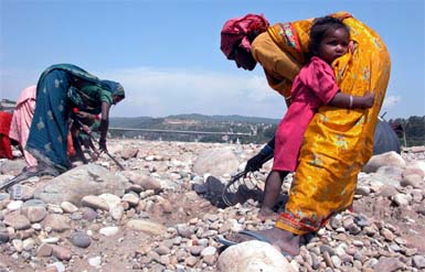 A girl hugs her mother as she works along with other labourers on the eve of International Labour Day