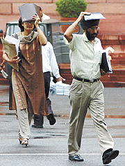 Visitors at Parliament House shielding themselves from the sudden downpour in the Capital on Monday