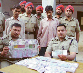 Policemen show fake currency as the accused look on in Ludhiana on Tuesday