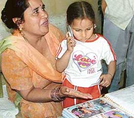 Aman identifies her relatives of the previous birth from a family album as her aunt, Ms Saroj, looks on at Saketri village