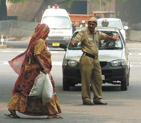 A policeman stopping traffic at a busy junction to help a woman cross the road in the Capital