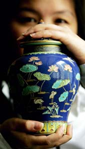 A model holds up a Famille Rose fahua style jar and cover with Qianlong impressed six character sealmarks from the period (1736-1795) prior to an auction at Christies in Hong Kong 