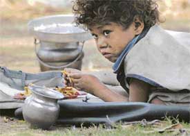 An impoverished child munches his lunch as his parents work nearby in Ludhiana on Friday