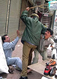 A policeman lathicharges traders protesting against VAT in Srinagar on Monday