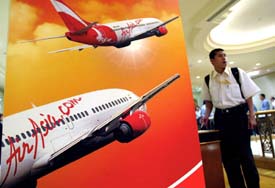 A man stands next to a banner promoting Asias top budget carrier AirAsia in Kuala Lumpur