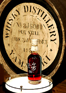 A bottle of 50-year-old single malt whisky is displayed in front of a cask barrelled in 1953 as Suntory unveiled Japans most expensive whisky called, Yamazaki 50-year, at a Tokyo hotel on Wednesday