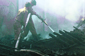 Fire Brigade personnel dousing flames at a warehouse where gunny bags containing wheat caught fire in Ludhiana on Sunday