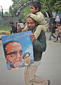 A Peoples Conference supporter carries a portrait of a former Hurriyat leader, the late Abdul Ghani Lone, and his son Sajjad Lone after a rally in Srinagar on Sunday.