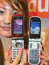 Ayako Toda, an employee of KDDI Corp, shows off the mobile phone carriers new models of 3G phones during a press conference in Tokyo on Monday. 