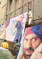 Workers remove the poster of the movie "Jo Bole So Nihaal" from a cinema hall in Ahmedabad on Monday. 