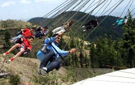 Tourists enjoy the swing ride at Fun Village, near Kufri, 25 km from Shimla, on Tuesday