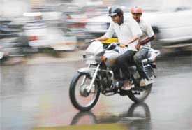 A motorcyclist and his pillion rider brave sudden showers that lashed Ludhiana on Thursday afternoon