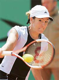 Justine Henin-Hardenne of Belgium plays a backhand shot during her match against Svetlana Kuznetsova of Russia in the fourth round of the French Open at Roland Garros