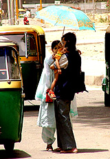 A woman tries to save her husband and child from the scorching sun in the Capital on Friday