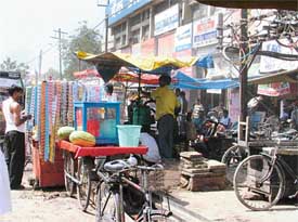 A cigarette vendor and a sugarcane crusher doing business close to Ghanta Ghar on Saturday