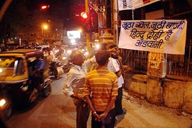 People watch an anti-Advani poster in Ahmedabad on Friday