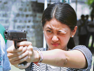 A Philippine journalist aims her pistol during a target practice at a military camp in Manila. 