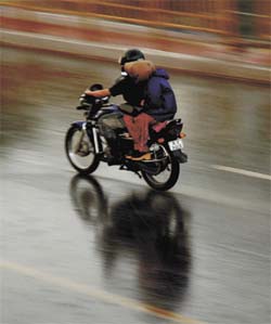 A couple on a motorcycle enjoying themselves during the afternoon storm in the Capital