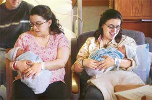 After giving birth at Rochester General Hospital in Rochester, New York, Rachel Haak, 28, holds her new-born son Ethan as her twin sister, Rebecca Bradstreet, right, holds her new-born daughter, Jane, in a hospital room
