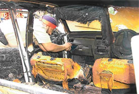 A cop examines the badly burnt car