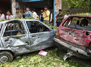 Kashmiris look towards the vehicles which were damaged in a heavy explosion in Pulwama, 39 km south of Srinagar, on Monday. 
