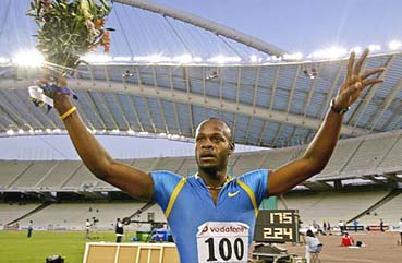 Asafa Powell of Jamaica celebrates after winning the 100 metres race by clocking 9.77 seconds, a new world record, in Athens