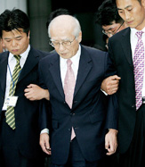 Kim Woo-choong, a former Chairman of the Daewoo Group, is escorted by investigating officers as he is transferred to a detention house from the prosecutors office in Seoul on Thursday.