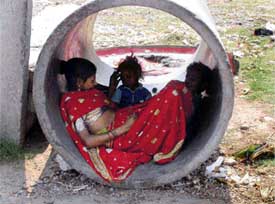 A labourer woman in Ram Darbar takes a respite with her two children in a drainage pipe on a hot afternoon