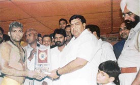 Mr Surinder Dawar, Parliamentary Secretary, Punjab, hands over the trophy to Dimpy who won the 13th Annual Wrestling Championship held in Ludhiana