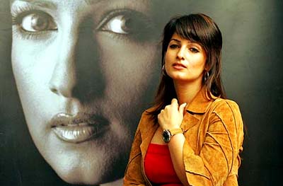 Actress Twinkle Khanna displays a watch from the latest collection of a Swiss watch manufacturer as she stands beside her poster during a launch ceremony in Kolkata on Friday