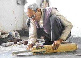 An artisan works diligently on a cricket bat in Shimla. 