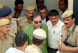 Former Indian cricket captain Mansur Ali Khan Pataudi is escorted by policemen after he surrendered in a case relating to recovery of carcasses of black bucks, in Jhajjar